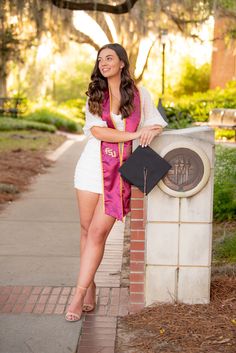 a beautiful young woman posing in front of a sign with her graduation cap on it