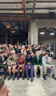 a group of people sitting next to each other in front of a crowd at a fashion show