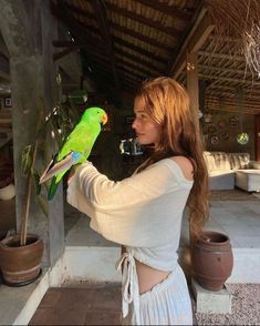 a woman holding a green parrot on her arm