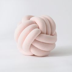 a ball of pink yarn sitting on top of a white surface with one knot in the middle