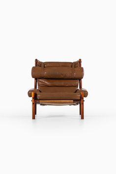 a brown leather chair sitting on top of a white floor next to a wooden frame