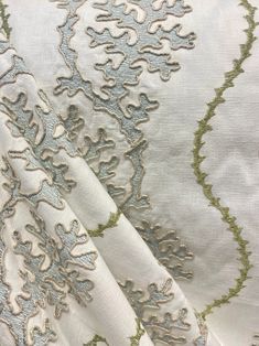 the fabric is white and green with an intricate design on it's side,