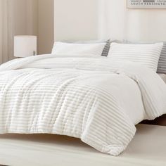 a bed with white comforter and pillows in a room