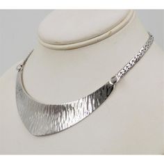 This is part of Chairish’s Costume Jewelry assortment.  Rhodium plated textured bib necklace with spring ring clasp. Unmarked but matching cuff (sold separately) is marked. Circa 1976 or 77 based on similarly styled bracelets and necklaces advertised in those years. Measures: 6 inches long by 4 1/4 inches wide. Center; 1 inch. Excellent condition.  Color: silver  Please reference the measurements noted in the description above for the best approximate dimensions. Please reach out to the seller u Elegant Hammered Silver Jewelry, Elegant Silver Hammered Jewelry, Metal Jewelry With Polished Finish For Anniversary, Modern Hammered White Gold Jewelry, Silver Bib Necklace In Costume Jewelry Style, Elegant Oxidized Metal Jewelry, Silver Bib Necklace Choker In Costume Style, Elegant Metal Jewelry With Oxidized Finish, Modern Jewelry With Sterling Silver Clasp