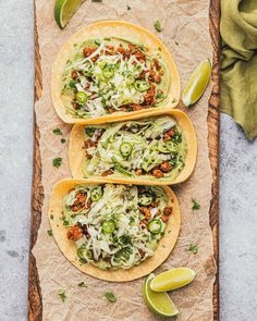 three tortillas filled with shredded cheese and toppings on top of parchment paper