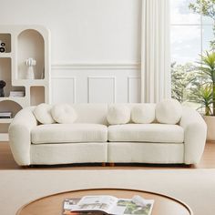 a living room with a white couch and coffee table in front of a book shelf