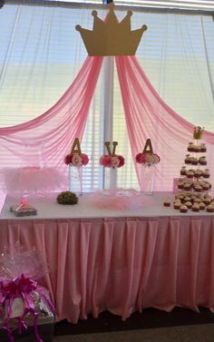 a table topped with cupcakes covered in frosting next to a pink curtain