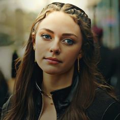 a woman with long hair and blue eyes wearing a black jacket is looking at the camera