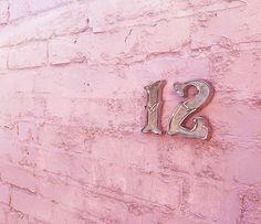 the number twelve is displayed on a pink brick wall