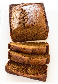 sliced loaf of banana bread sitting on top of a white plate next to another loaf