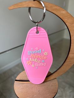 a pink plastic keychain with the words good things take time written on it