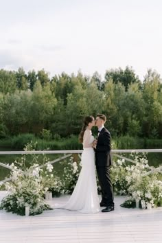 a bride and groom standing next to each other in front of white flowers on the ground