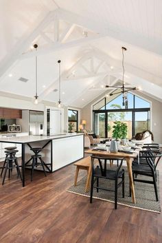 an open concept kitchen and dining area with wood flooring, white walls and vaulted ceiling