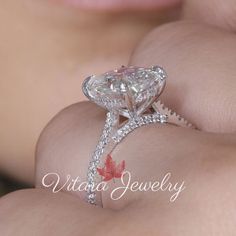 a woman's hand holding an engagement ring with a pear shaped diamond on it