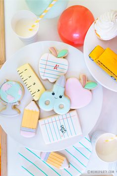 decorated cookies and cupcakes are on a white plate next to other desserts