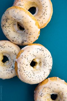 four donuts with white frosting and black sprinkles on blue background