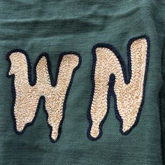 the letters w and w are embroidered onto an old green jacket with sequins