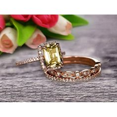 a yellow diamond ring sitting on top of a wooden table next to pink tulips