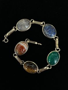 Antique Art Deco 14k Gold Multi-Gemstone Carved Scarab Bracelet 7.5"  Item here is an antique Art Deco 14k gold multi-gemstone carved scarab bracelet. This bracelet features stones such as sardonyx, tiger's eye, chalcedony, lapis, and quartz. Bracelet is marked 14k gold and closes with a spring ring.  Condition: Good; item is pre-owned and may have some signs of light use and age related wear. Please look closely at the pictures provided as they are an extension of our written description. Measurements: Length: 7.5 in Width: .5 in Weight: 8.4 dwt 8731F Antique Oval Gemstone Bracelets, Antique Multicolor Oval Jewelry, Vintage Adjustable Gemstone Cuff Bracelet, Antique Gold Cabochon Bracelets, Antique Multi-stone Bracelet For Formal Occasions, Antique Multi-stone Bracelets For Formal Occasions, Antique Multi-stone Bracelets As Gift, Vintage Gemstone Cuff Bracelet Collectible, Art Deco Multi-stone Sapphire Jewelry