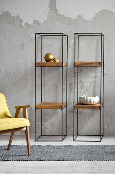 two metal shelves with wooden shelves and yellow chairs in front of a wall painted gray