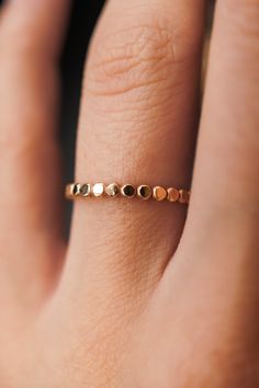 a woman's hand with a gold ring on top of her finger and two dots in the middle