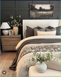 a white bed sitting in a bedroom next to a night stand with flowers on it