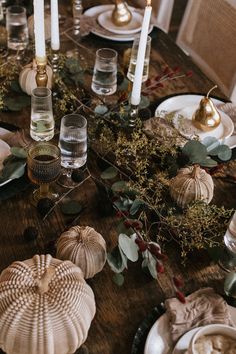 a wooden table topped with plates and candles