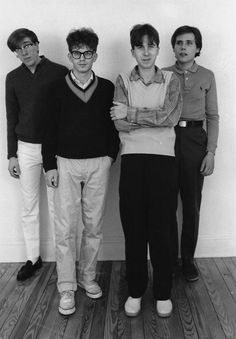 black and white photograph of four people standing next to each other in front of a wall