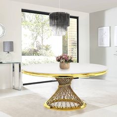 a white and gold dining room table with flowers in a vase on the center piece