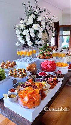 an assortment of fruits and snacks on a buffet table with flowers in the background at a wedding reception