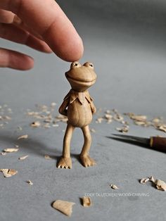 a tiny wooden frog standing on its hind legs