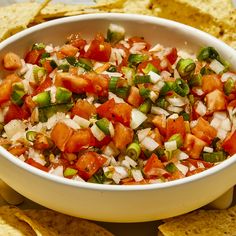 a white bowl filled with salsa surrounded by tortilla chips