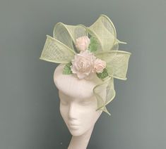 A truly elegant statement fascinator in white and mint green straw with bow and floral detailing.  This beautiful circular straw headpiece is made in classic white and features a large sculptural double bow in pale green with twisted tails.  Seated within the bow is a white silk dupion rose with silk organza layered petals. Surrounding the rose are two matching rose buds, and silk dupion leaves in a soft pale green.  Measuring a circular 17cm, this headpiece is fitted with a fine elastic in a colour to match your own hair colour. The elastic sits to the back of the head and underneath the hairline, ensure a totally invisible fit. This headpiece is lined in matching felt to give an opaque look and solid colour.  The perfect choice for Royal Ascot, a wedding, or other special occasion where Fasinators Ideas, Green Hat Fascinator For Wedding, Spring Green Fascinator For Races, Pale Green Wedding, Green Spring Evening Fascinator, Mint Green Fascinator, Adjustable Hat-shaped Wedding Fascinator, Green Fascinator, Hat With Bow