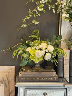 a vase filled with white flowers sitting on top of a table next to two books