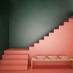 an empty room with stairs leading up to the top floor and two bowls on a table