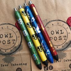 three pens sitting on top of a piece of paper next to each other in front of a brown bag