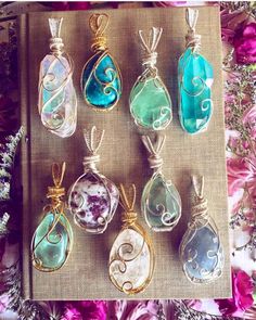 seven glass pendants are sitting on a book with flowers in the backgroud