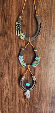 three necklaces hanging on a wooden wall with beads and feathers attached to the strings