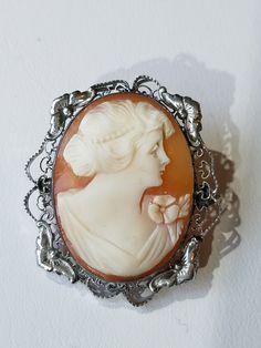 "This Victorian Sterling Silver Cameo Brooch features a Pinkish Shell in an oval shaped octagonal frame, hand carved with a Lady Facing Right. The base metal has intricate Silver metal work with elegant flowers on both sides and bottom side frames. The brooch has an early safety catch and secure. It has the hallmark \"STERLING\" across the inner rim. When you put the brooch up to the light it is transparent. This brooch makes a excellent Christmas Gift or Mother's Day Gift. Will arrive in a gift Ornate Oval Engraved Brooches, Ornate Oval Intaglio Brooches, Oval Engraved Brooches For Collectors, Intricate Design Brooches As Gifts, Engraved Oval Brooches For Wedding, Ornate Cameo Brooches For Collectors, Ornate Cameo Brooch, Art Nouveau Filigree Brooch For Collectors, Collectible Art Nouveau Filigree Brooches