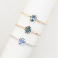 three different colored rings sitting on top of a white napkin with gold and silver accents