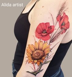 a woman's arm with red flowers and grass on the left side of her body