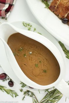 two white serving dishes filled with food on top of a table next to bread and cranberries