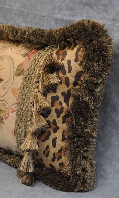 a leopard print pillow with tassels on the edges and fringe trim around it