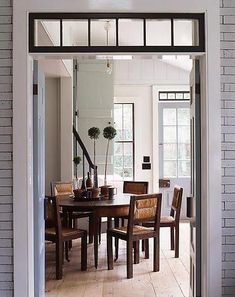 a dining room table and chairs in front of a brick wall with an open door