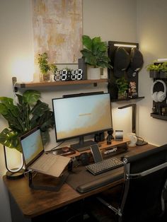 Cozy and well-organized desk setup in a home office, featuring a large monitor with 'DISCIPLINE' on the display. The desk is surrounded by lush houseplants, a stylish abstract painting, and various functional gadgets including a digital clock and a headphone stand. The workspace is equipped with a laptop on a stand, a mechanical keyboard, and a classic office chair, all under soft ambient lighting Apartment Bedroom Ideas With Desk, Closet Desk Setup, Desk Ideas Men, Mid Century Modern Desk Setup, Small Study Desk Ideas, Natural Desk Setup, Mens Desk Setup, Couple Desk Setup, Desktop Set Up