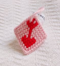 a crocheted pink and red object on a white blanket