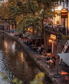 people sitting at tables on the side of a river