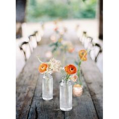 two vases filled with flowers sit on an old wooden table in front of the camera