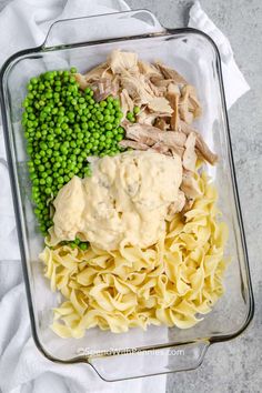 a glass dish filled with pasta, peas and chicken