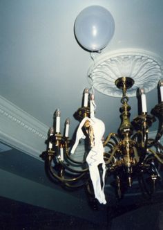 a chandelier with two white balloons hanging from it's sides and one light on the ceiling